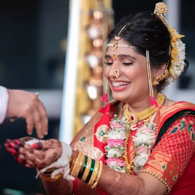The joy of a Maharashtrian bride during her wedding ceremony. Her radiant smile is the centerpiece, enhanced by a classic makeup look and traditional gold jewelry.