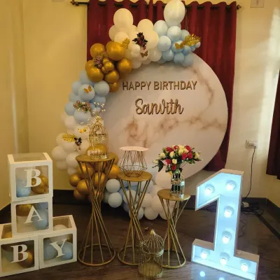 A chic first birthday setup with a blue, white, and gold balloon arch over a marble-print circular backdrop, perfect for a modern celebration.