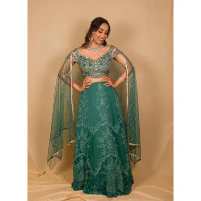 This teal green lehenga is a beautiful option for a reception or sangeet. It features delicate silver embroidery and modern cape-style sleeves for a touch of drama.