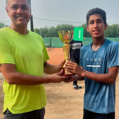 Harsh Nandal, winner of the U16 boys' title at a UTR tournament, receives his trophy from a coach. His smile reflects the hard work that goes into preparing for and winning these events.