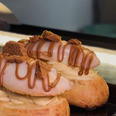 Biscoff-topped filled buns sit together on our counter, finished with piped cream and a caramel-coloured drizzle.