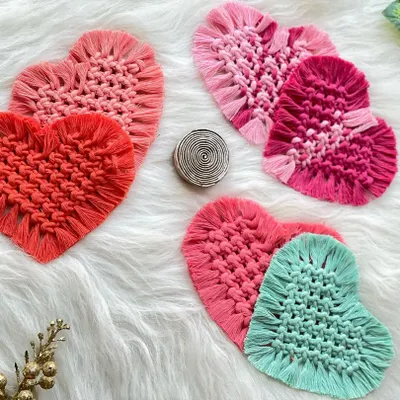 A collection of my heart-shaped macrame coasters in various shades of pink, red, and teal. They are perfect for adding a pop of color and love to your coffee table.