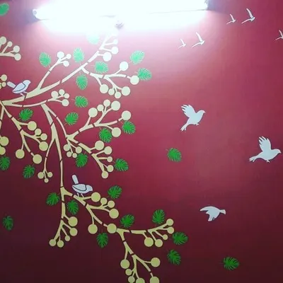 This vibrant red accent wall is brought to life with a nature-themed stencil. The design features a stylized tree, leaves, and birds, creating a cheerful and dynamic atmosphere in the room.