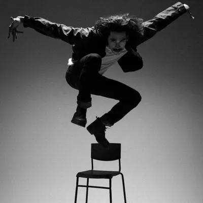 A high-energy, gravity-defying shot of actor Vishak Nair for an editorial. The simple black jacket, white tee, and dark jeans create a classic, rebellious look inspired by rock and roll.