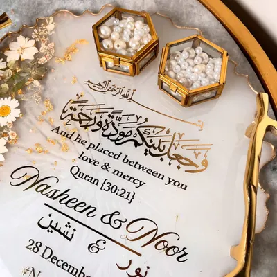 A close-up of an elegant white and gold resin tray. This design features delicate daisy accents, gold leaf flakes, and a beautiful Quranic verse about love and mercy.