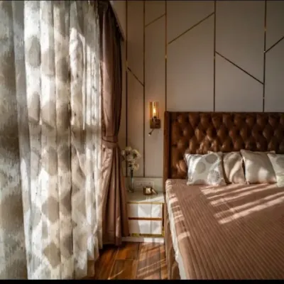 Waking up here feels like a dream. The morning light filters through the sheer curtains, highlighting the geometric wall paneling and the plush, tufted headboard that serves as the room's centerpiece.