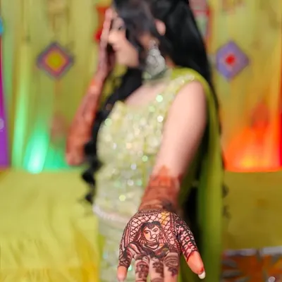 A close-up of a bride's portrait drawn on the palm, complete with a veil (ghunghat) and jewelry. This is a popular choice for brides who want a truly personal touch in their mehandi.