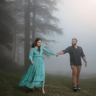A couple walks hand-in-hand through a misty forest, creating a dreamy and romantic atmosphere for their anniversary photoshoot in the mountains.
