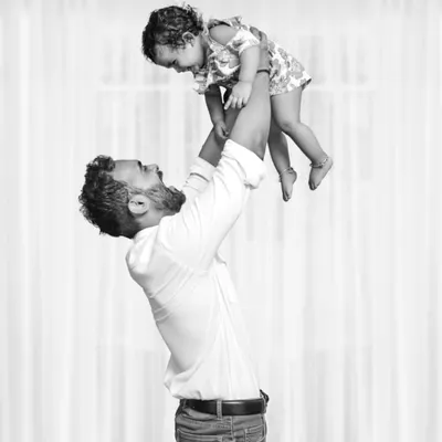 A powerful black and white shot of a father joyfully lifting his daughter into the air, capturing a moment of pure happiness and the special father-daughter bond.