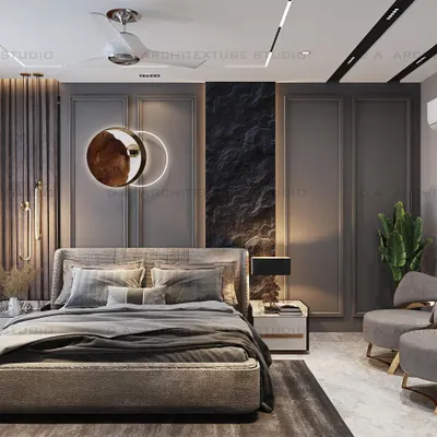 A master bedroom in Meera Bagh featuring a dramatic, dark-textured accent wall with a unique circular light fixture. The design balances bold elements with cozy, comfortable furnishings.
