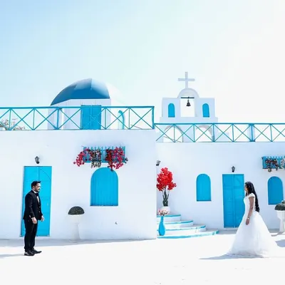 For this pre-wedding shoot, we used a stunning Santorini-style location to create a dreamy, romantic backdrop. This wide shot captures the beautiful architecture and the couple's elegant poses, perfect for a save-the-date announcement.
