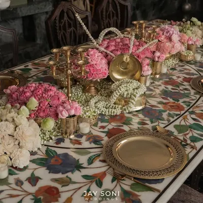 Dinner table settings that are anything but simple. For this wedding, I designed a tablescape on a stunning marble inlay table, featuring pink roses, jasmine garlands, and traditional brass plates for a refined and memorable dining experience.