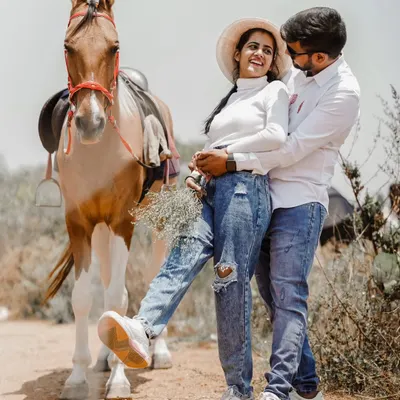 A fun and rustic shot with a horse, where the couple's casual denim outfits create a relaxed and playful vibe.