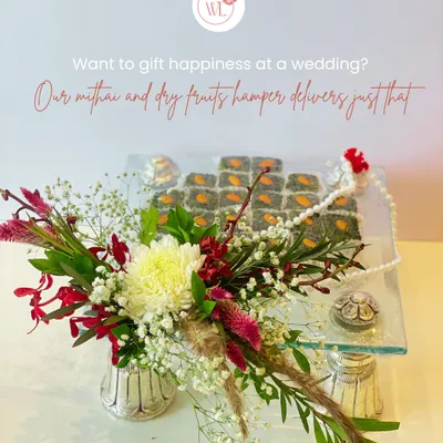 This is my classic mithai and dry fruits hamper, designed to deliver happiness. Here, I've arranged gourmet pistachio sweets on a clear glass tray, accented with a fresh floral bouquet and traditional elements.