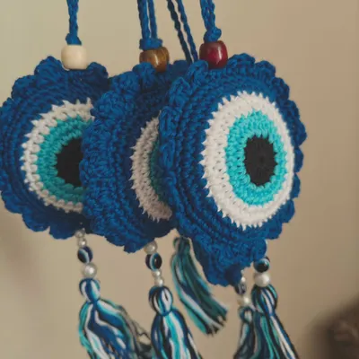 A set of my crochet Evil Eye car charms, ready to protect against bad vibes. Each one is made with deep blue, white, and turquoise yarn and finished with a tassel.