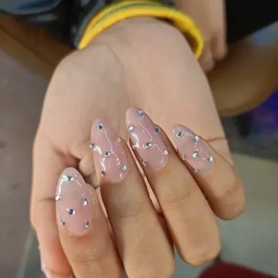 A simple yet stunning look. These long, almond-shaped extensions have a sheer pink base and are adorned with scattered silver rhinestones for a "diamond rain" effect.