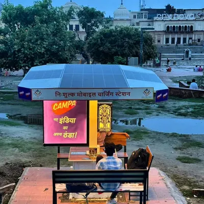 A visitor uses our Smart Solar Hut at Ram Ki Paidi in Ayodhya, with the historic ghats in the background. The solar panels on the roof are clearly visible, highlighting the sustainable nature of the installation.