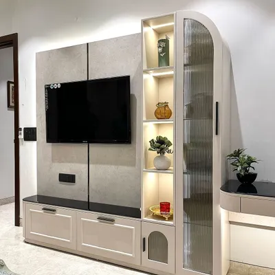 A closer view of our multi-functional TV unit. The design includes a tall cabinet with fluted glass for display, drawers for storage, and an attached, backlit study table, all in one cohesive piece.