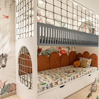 This custom bunk bed is the star of the room, with a sleeping area below and a netted play area on top. The jungle-themed wallpaper and animal-print bedding create a fun, immersive environment for a growing boy.