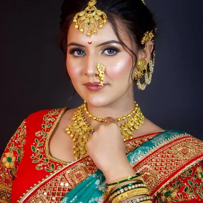The quintessential Maharashtrian bride, complete with a traditional nath and layered gold jewellery. This look combines classic elements to create a timeless and elegant style.
