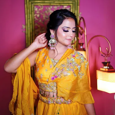 This vibrant yellow lehenga with a modern cape-style blouse is perfect for a Haldi ceremony look. The colorful embroidery adds a festive touch.