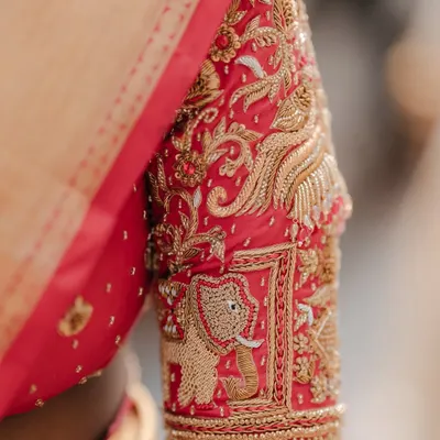 A close-up of the sleeve of the bride's blouse, featuring magnificent elephant and bird motifs in zardosi embroidery.