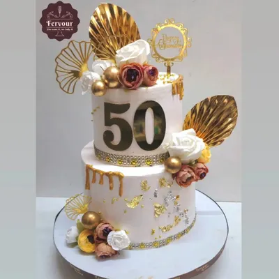 A stunning two-tier cake for a 50th anniversary, decorated with gold drip, delicate fans, and florals. This chocolate mousse cake is a perfect example of how I create elegant designs for golden celebrations.