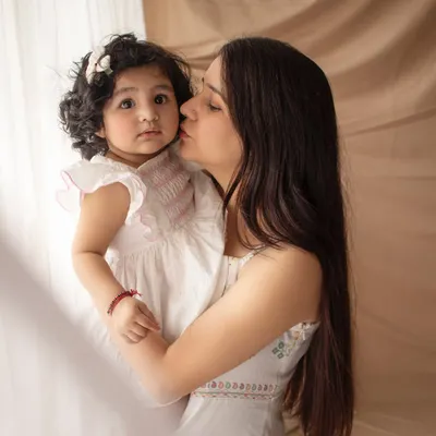 A mother's gentle kiss. This close-up, candid moment is so full of love and tenderness, captured in our soft and neutral boho setting.