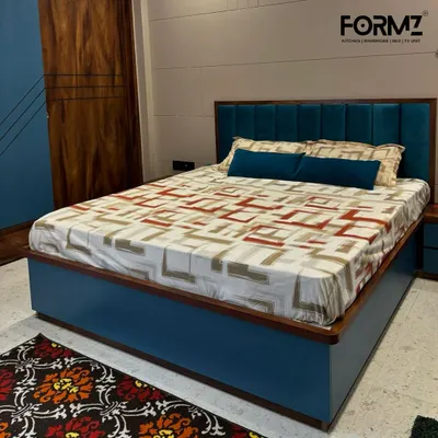 This bedroom showcases our ability to deliver a complete furniture solution. The dark wood wardrobe in the background is designed to perfectly match the custom bed, which features a vibrant blue upholstered frame and headboard for a contemporary look.