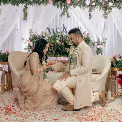 A tender moment during the ring ceremony, with the groom on one knee. The floral decor and scattered petals create a truly romantic setting.