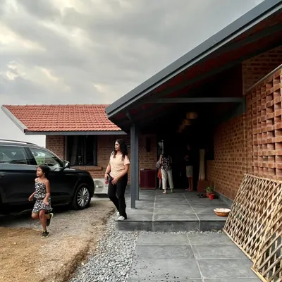 The entrance to the NallaNela farmhouse, a rustic weekend home built with exposed brick. The design features a welcoming covered porch and a simple, functional layout for family getaways.