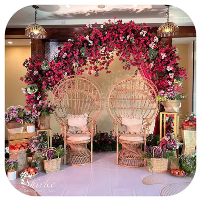 A unique and bohemian-inspired seating area for a Mehendi or Haldi. We used peacock-style wicker chairs and a stunning backdrop of fuchsia bougainvillea to create a vibrant and stylish photo corner.