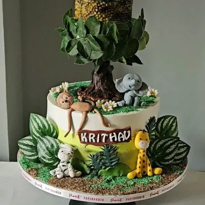 This jungle-themed cake has a special surprise: a revolving top tier. The entire scene, with its handmade edible animals and wafer paper tree, comes to life, creating a dynamic and exciting centerpiece for a child's birthday.