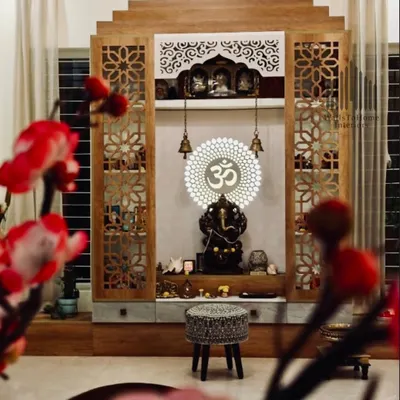 A beautifully framed shot of a completed pooja unit, showcasing the intricate jali work doors, backlit 'Om' symbol, and the serene atmosphere it creates.
