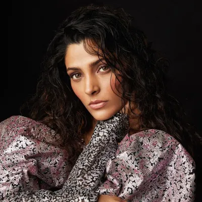 A portrait of actress Saiyami Kher for a Filmfare magazine feature. The styling focuses on a romantic yet bold look, with a metallic printed dress with voluminous puff sleeves and soft, natural makeup.