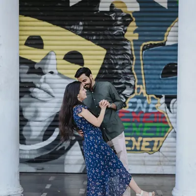 A dynamic shot of a couple dancing in Connaught Place, Delhi. The vibrant street art provides a cool, modern backdrop that perfectly matches their energetic and fun-loving personalities.