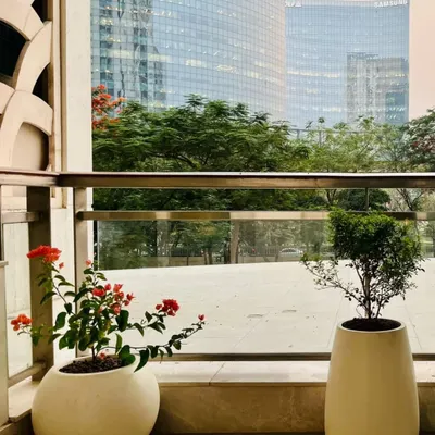 A serene balcony we designed for Mr. Lokvir Kapoor, Co-founder of Pine Labs, at DLF Camellias. The minimalist design features elegant planters against the stunning backdrop of the city skyline, creating a peaceful urban escape.