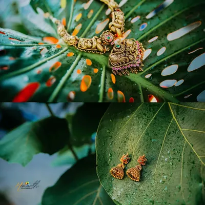 A creative shot of the bride's traditional temple jewelry, artistically placed on large green leaves. This highlights the intricate craftsmanship of the pieces.