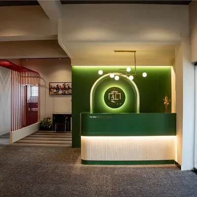 A wide shot of my studio's entrance, featuring the bold green reception desk and a view into the collaborative zones, defined by red mesh partitions.