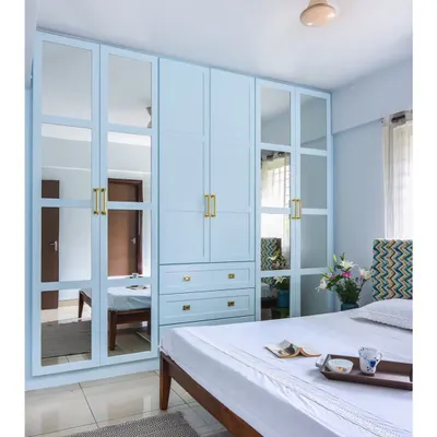 This is one of our most-loved wardrobe designs. The powder blue finish, mirrored panels, and elegant brass handles create a look that is both classic and fresh, while maximizing storage and light.