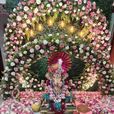 A truly grand floral arch for a beloved Ganpati idol. This massive arrangement uses thousands of pink and white flowers against a green wall, with warm lights that make the entire setup look divine and welcoming.