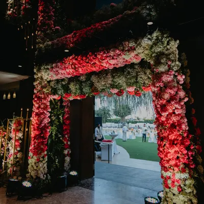 A grand entrance is the first chapter of your wedding story. We created this magnificent, dense floral archway in shades of red and pink to give guests a breathtaking glimpse of the celebration waiting inside.