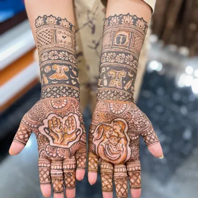 A detailed look at a custom baby shower mehendi design. This features a portrait of the new family, baby clothes, and the due date, all woven into traditional patterns. It's a beautiful way to capture the excitement of this special time.