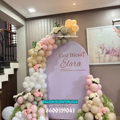 An elegant and modern naming ceremony backdrop with the message "God Bless Elara". The soft, muted tones of the balloons and the clean arched backdrop create a sophisticated and heartfelt setting.