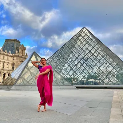 Striking a dance pose in a saree in front of the iconic Louvre Pyramid in Paris. This image is a beautiful fusion of Indian tradition and world-famous architecture.