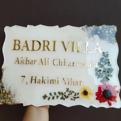 A custom resin house nameplate I created for 'Badri Villa'. It features the family name and address in gold acrylic letters, with a border of preserved flowers and gold leaf.