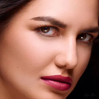 A classic beauty headshot. The focus here is on flawless skin and a strong, direct gaze. The lighting is carefully controlled to be soft yet defining, perfect for a skincare or makeup ad.