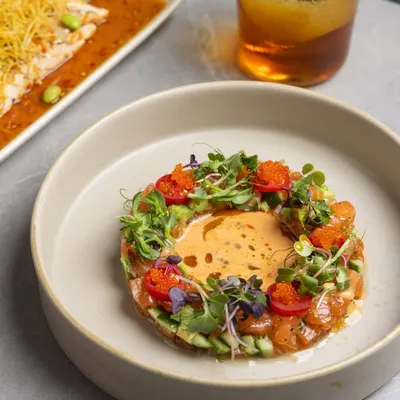 The beauty of a plate is in the details. Here, a salmon tartare is presented alongside a perfectly seared fish, showcasing how the sauce holds and the garnish finishes the dish.