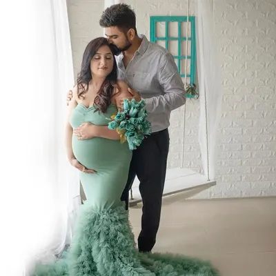 A tender moment captured by the window. The soft natural light and the flowing green gown make this maternity portrait feel so serene and beautiful.
