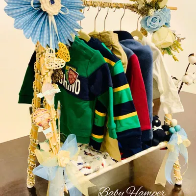 A close-up of our unique baby boy clothing rack hamper. This gift features a collection of stylish baby outfits, creatively displayed and decorated with blue ribbons and handcrafted details for a memorable presentation.